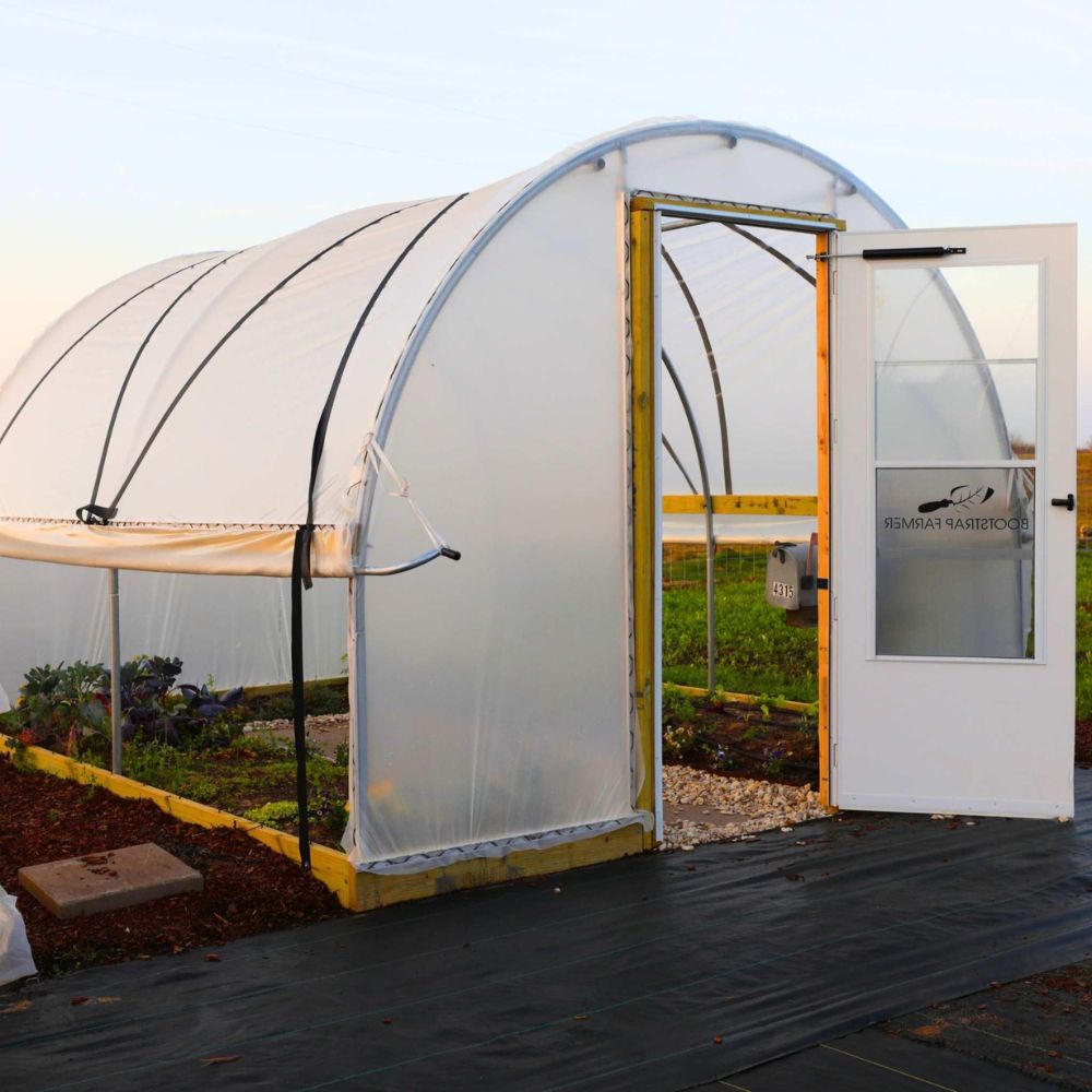 Bootstrap Farmer 10' × 12' Hobby Greenhouse shown with optional batten straps, roll-up side, End Wall Door Frame Kit, and customer-supplied door