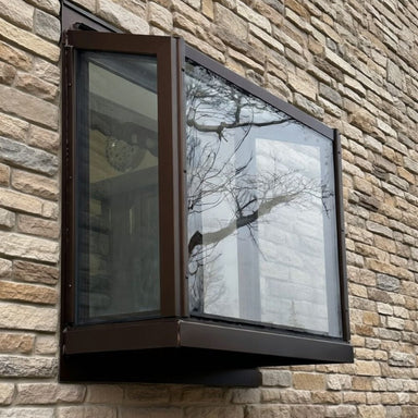 Bronze Janco Garden Window installed on a stone exterior wall