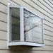 White Janco Garden Window installed on exterior siding, shown from an angled view