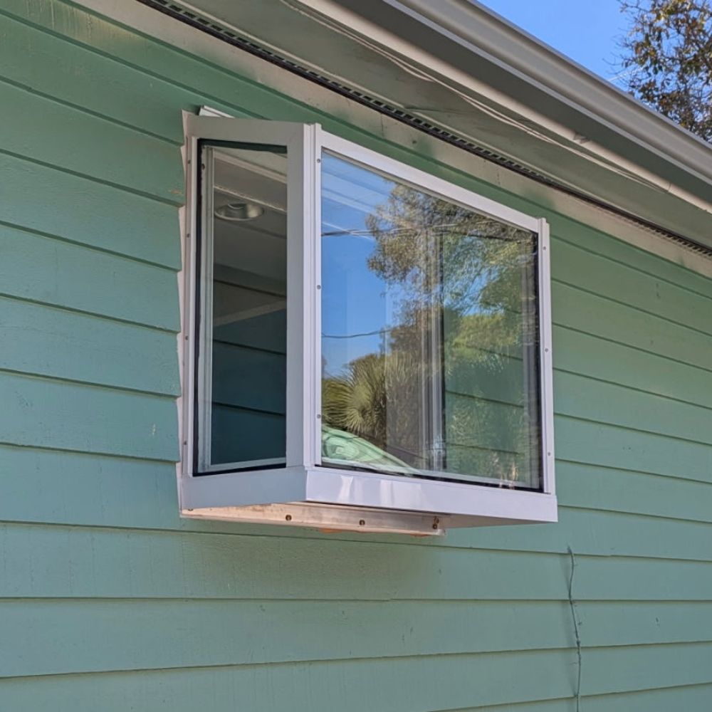 White Janco Garden Window installed on a green-sided home exterior, shown from an angled view