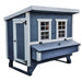 A blue and white chicken coop featuring a single door, two multi-paned windows, and a front-mounted nesting box.