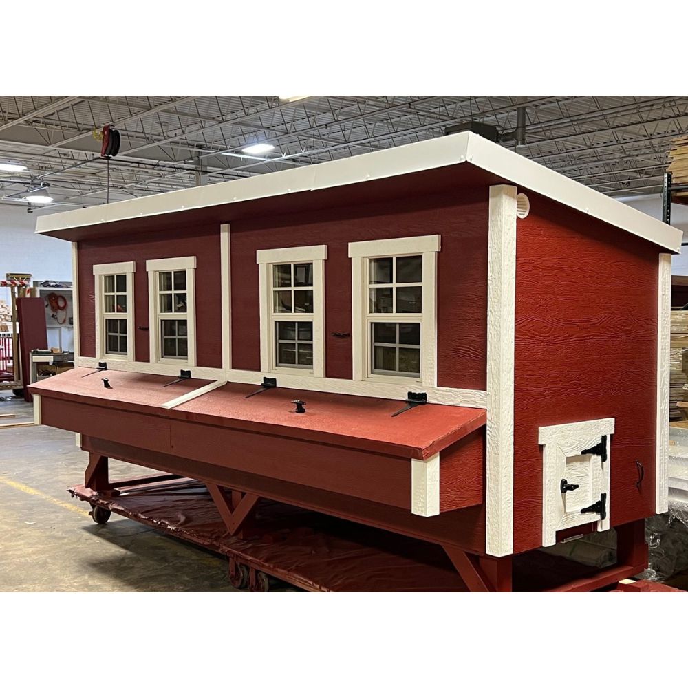 Red and white wooden chicken coop, front quarter view with small chicken access door.