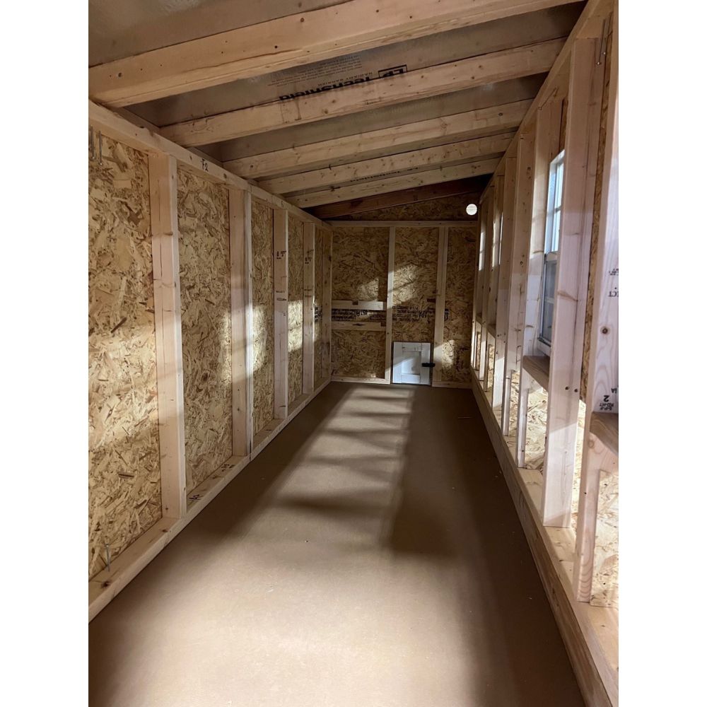 Interior of a large chicken coop showing nesting box openings on right and chicken access door straight ahead.