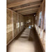 Interior of a large chicken coop showing nesting box openings on right and chicken access door straight ahead.