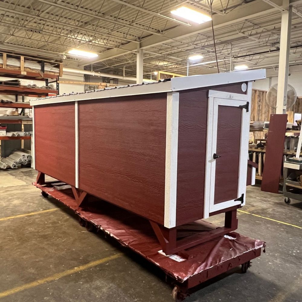 Back view of a red and white chicken coop at assembly warehouse.