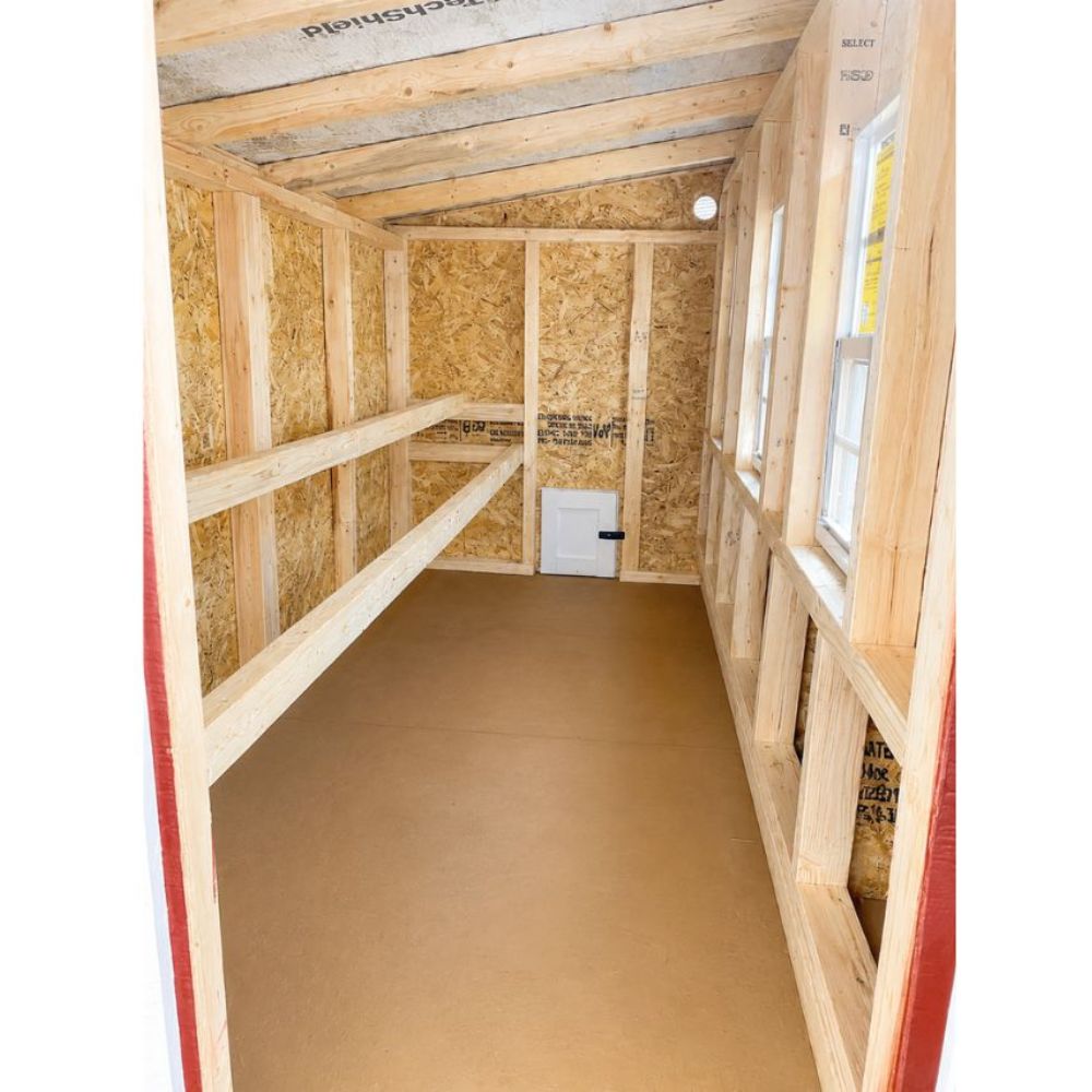 Wooden interior of XL chicken coop with roosting bars on the left and nesting box openings on the right.