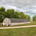 Bootstrap Farmer 20' DIT Hoop House Kit exterior in a field with a cloudy sky.