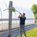 Person assembling a metal arch for the Bootstrap Farmer DIY Gothic Greenhouse beside a covered greenhouse structure