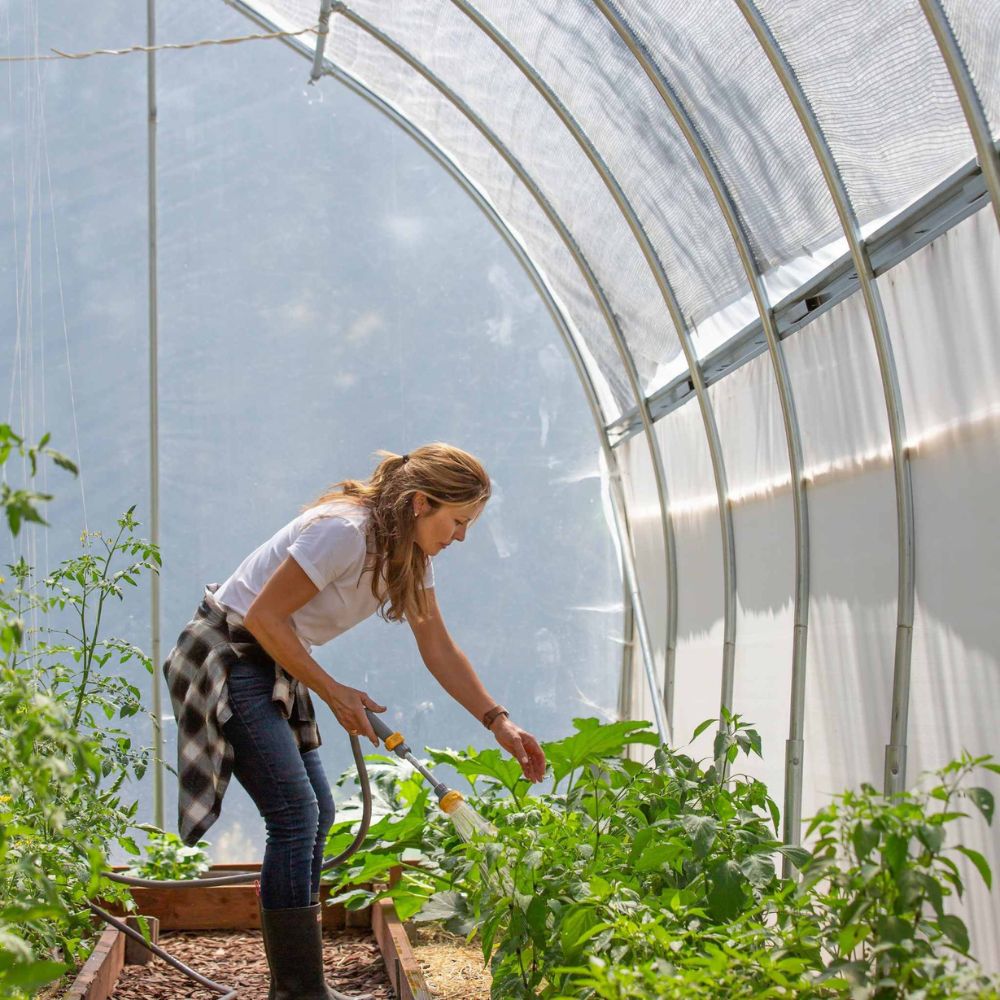 A woman tending plants in the Bootstrap Farmer Gothic High Tunnel.