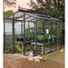 Janco Palmetto 8' x 10' glass greenhouse with bronze aluminum frame and plants inside.