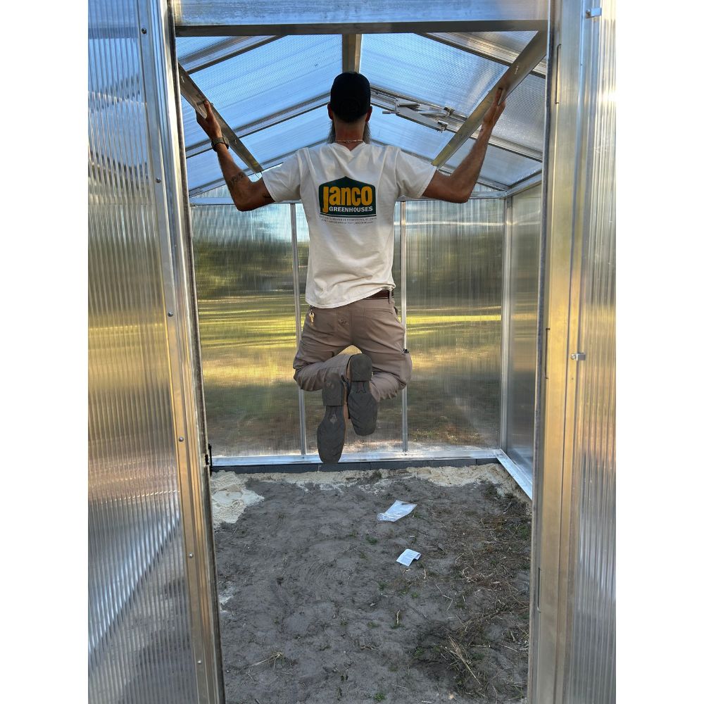 Interior view of Janco Palmetto greenhouse with aluminum framing and polycarbonate panels during installation